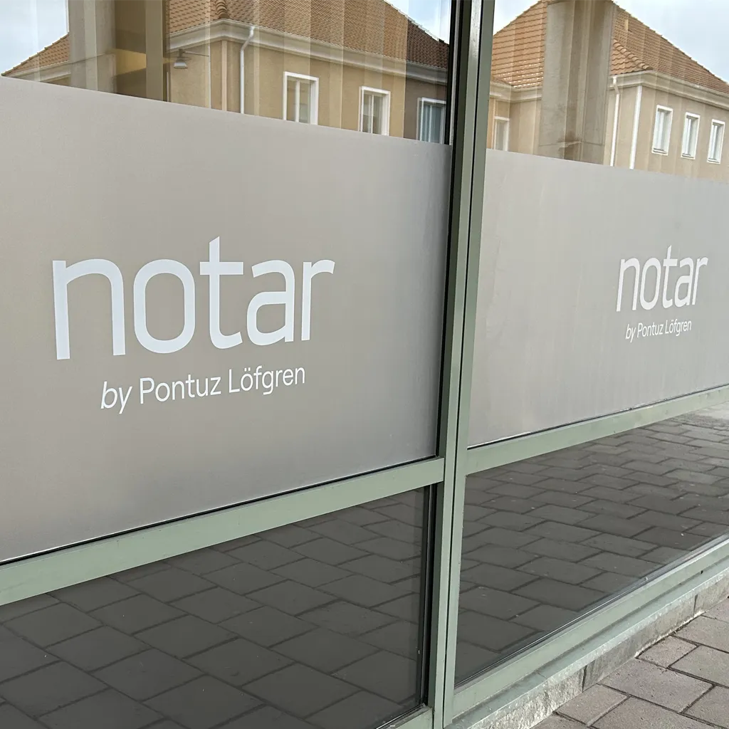 Frostad folie med utskuren logotyp monterad på fönster Notar i Kalmar